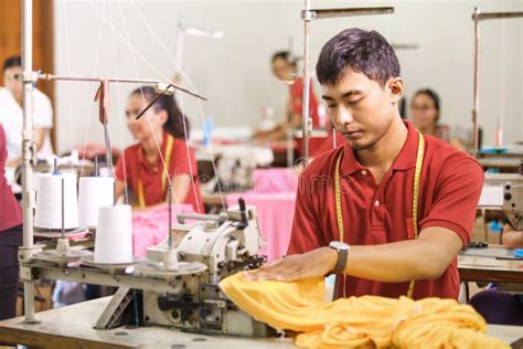 Seamstress In Textile Factory Smiling While Sewing With Industr Stock