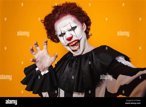 Shocking clown man 20s wearing black costume and halloween makeup