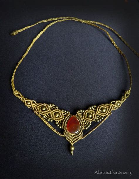 A Gold Necklace With A Red Stone On Its End And An Intricate Design