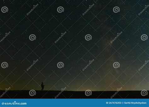 Back View Of Man With Flashlight Standing On Green Grassy Field Under