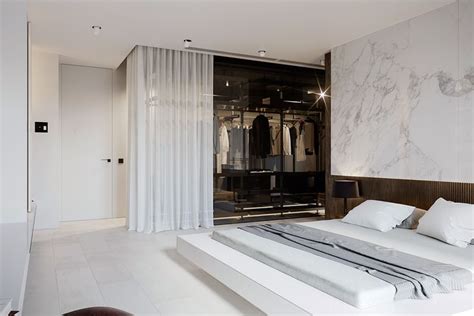 A Bedroom With Marble Walls And Flooring White Bedding And Closets
