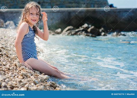 Happy Child Girl In Swimsuit Relaxing On The Beach And Playing With
