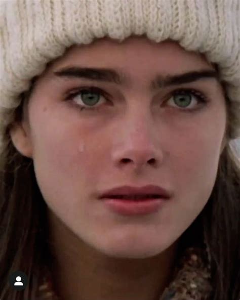 A Woman Wearing A White Beanie And Looking At The Camera With Tears On