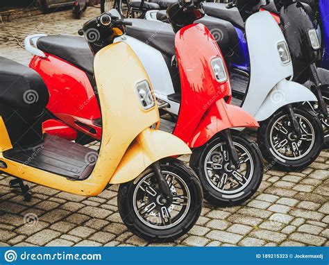 Electric Motorcycles Of Different Colors Stand In A Row On A Stone