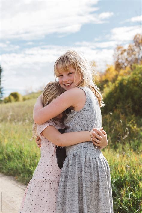 Young Girl Hugging Shy Sister By Stocksy Contributor Carey Shaw