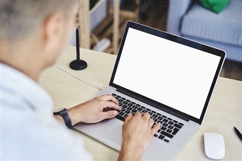 Young Man Typing On Laptop In Home Office Stock Photo