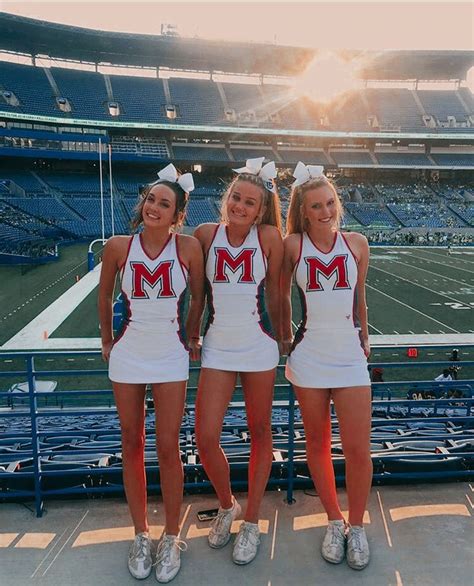 three cheerleaders posing for a photo at a football game