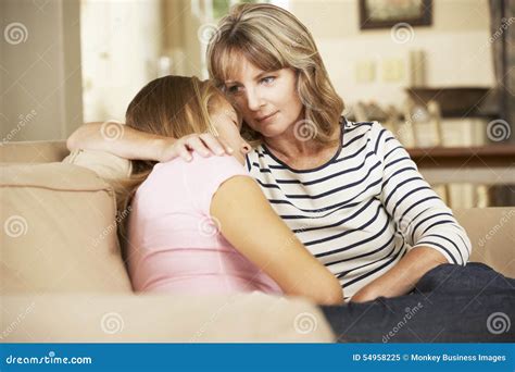 Madre Que Conforta A La Hija Adolescente Que Se Sienta En Sofa At Home