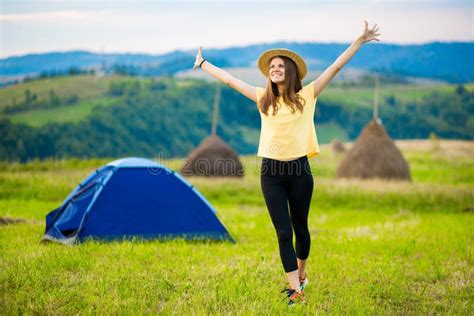 Happy Woman In Hat Stretching To Sun After Night In Tent On Top Of