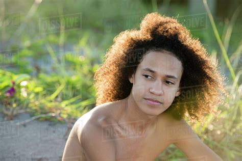 Mixed Race Teenage Boy Sitting On Beach Stock Photo Dissolve