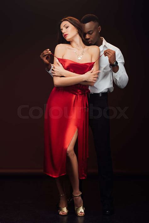African American Man Undressing Beautiful Woman In Red Dress Isolated