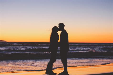 free photo couple kissing on the beach against beautiful sunset
