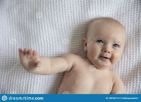 Happy 6 Month Old Baby Laying On A White Blanket Laughing Stock Photo