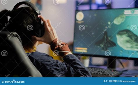 Focused Woman Gamer Sitting On Desk Putting On Headset Stock Image