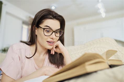 A Girl In Glasses Lying On The Sofa Reading A Book Stock Image Image