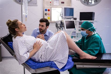 Doctor Examining Pregnant Woman During Delivery While Man Holding Her