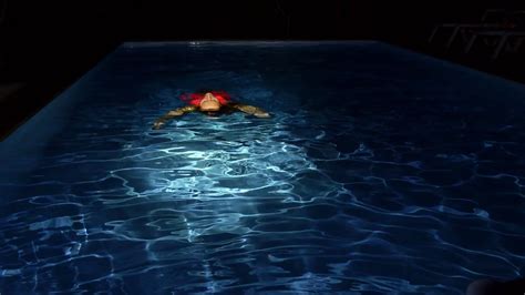 Young Woman Swims In The Pool On Her Back At Night Slow Motion Stock