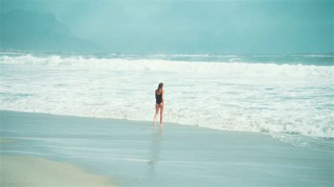 woman walking toward the waves · free stock video