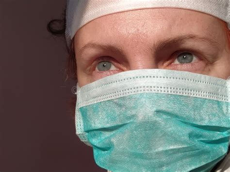 redhead woman with sick tired eyes in a protective surgical mask of green color gray eyes and