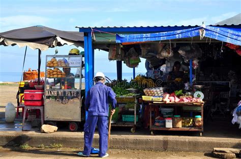 A Man Is Sweeping In Front Of His Food Street Vendor On The Con Dao