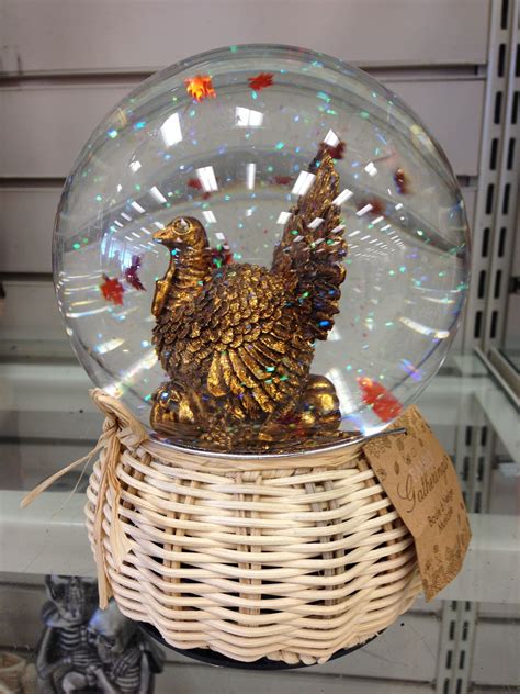A Snow Globe With A Golden Chicken In It Sitting On Top Of A Wicker Basket