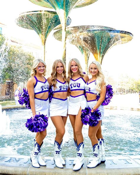 Three Cheerleaders Are Posing In Front Of A Fountain