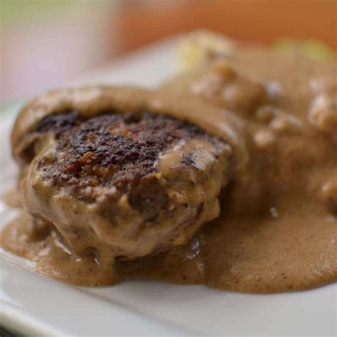 An old fashioned recipe of deliciously seasoned beef with a from scratch onion brown gravy. Hamburger Steak with Country Gravy | Small Town Woman