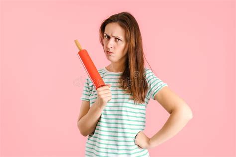 the angry brunette pursed her lips in displeasure and threateningly holds a rolling pin in her