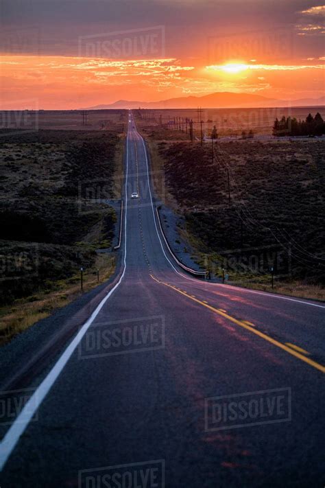 Cars Driving On Remote Road At Sunset Stock Photo Dissolve