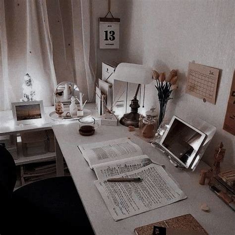 A White Desk Topped With A Laptop Computer Next To A Book And Flower