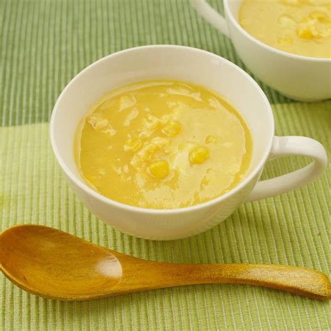 Two White Bowls Filled With Corn Soup On Top Of A Green Place Mat Next