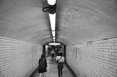 Grayscale View Of People Walking Through Tunnel Stock Image Image Of