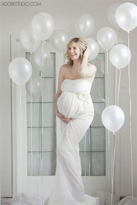 A Pregnant Woman Standing In Front Of White Balloons With The Caption Adore I Am In Love With