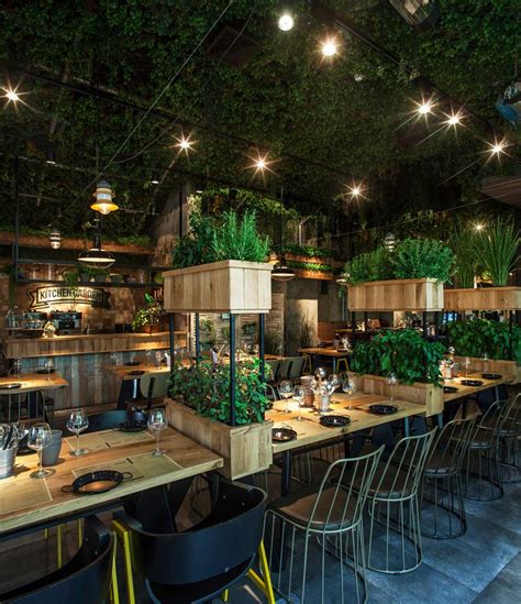 An Indoor Restaurant With Tables And Chairs Covered In Plants On The