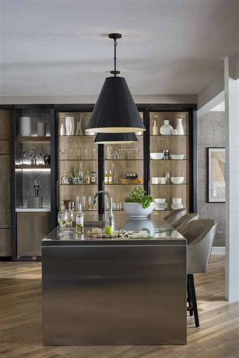 Metal kitchen cabinets are a reminisce of the 1940s. Stainless steel waterfall countertop, glass front cabinets with steel frame doors // R ...