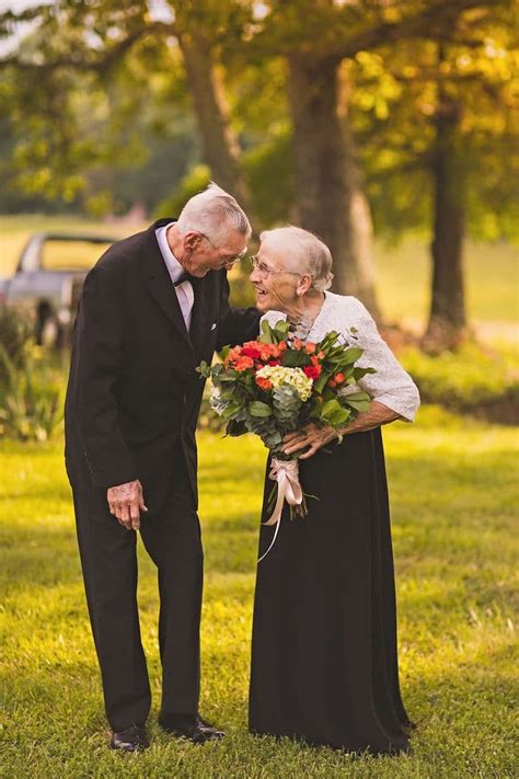 An Older Couple Standing Next To Each Other In The Grass