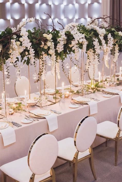 A Long Table Is Set With White Flowers And Candles For An Elegant