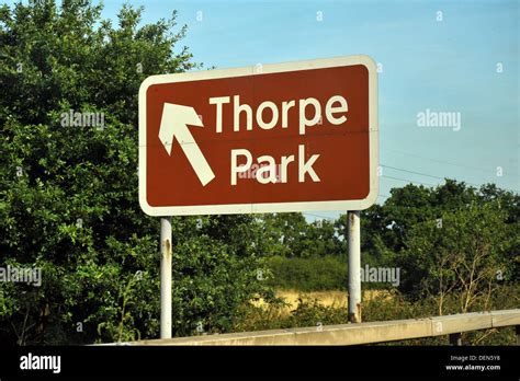 A Brown British Road Sign Directing Traffic To Thorpe Park Stock Photo