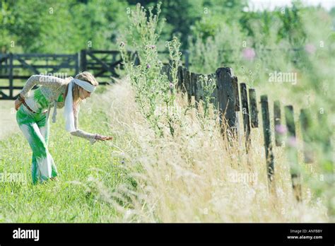 Young Woman Bending Over To Touch Tall Grass Side View Stock Photo Alamy