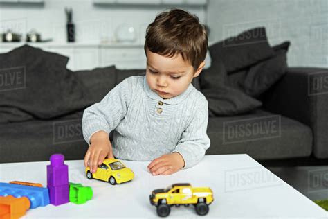 Selective Focus Of Little Kid Playing With Toy Cars At Table In Living
