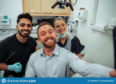Caucasian Male Taking Selfie With Male And Female Nurse Wearing Surgical Masks In Doctors Office