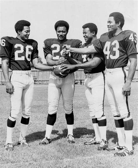 Four Football Players Are Standing Together On The Field