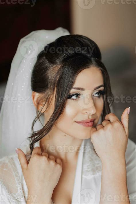 portrait of a brunette bride touching her face gorgeous make up and hair voluminous veil