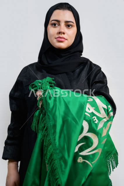 بورتريه لسيدة عربية خليجية سعودية ترتدي العباءة الخليجية تحمل بيدها علم