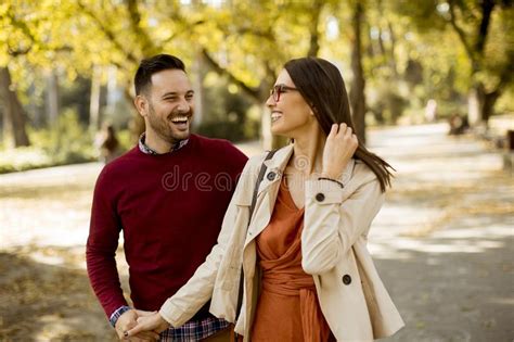 Young Woman And Man Walking In City Park Holding Hands Stock Image