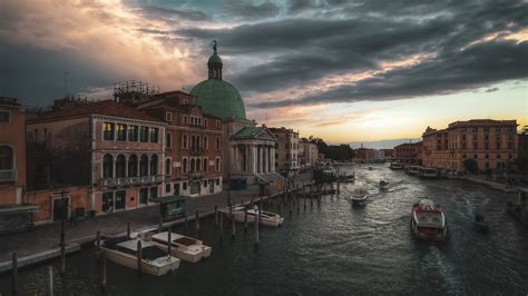 Boats On River Between Buildings Under Black Cloudy Sky In Italy Venice