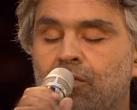 A Close Up Of A Person Holding A Microphone In His Hand And Singing Into It