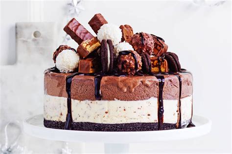 A Cake With Chocolate And Marshmallows On Top Sitting On A White Pedestal