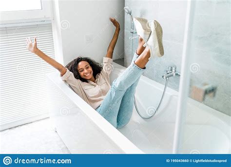 View Of African American Woman Lying In Bath With Outstretched Hands