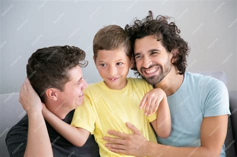 Padres Gays Alegres E Hijo Sentados Juntos En El Sofá Y Abrazándose